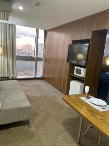 a living room with a table and a large window at Promoção - Flat em Brasília in Brasilia