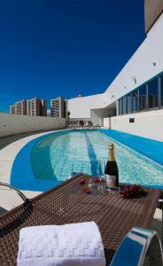 a bottle of wine sitting on a table next to a swimming pool at Promoção - Flat em Brasília in Brasilia