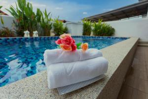 een stapel handdoeken op een richel naast een zwembad bij Relax Pool Villa Near Walking Street,jacuzzi ,BBQ 5Bed 6Bath City house54 in Pattaya South