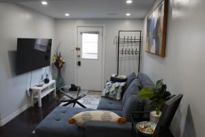 uma sala de estar com um sofá azul e uma televisão em Patio privé, hébergement équipé et spacieux. em Hamilton