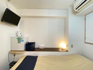 um pequeno quarto com uma cama e uma televisão numa prateleira em Tabist Hotel Aurora Ikebukuro em Tóquio