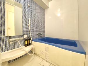 uma casa de banho com uma banheira azul e um espelho. em Tabist Hotel Aurora Ikebukuro em Tóquio