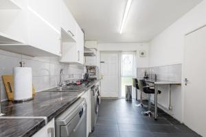 a kitchen with white cabinets and a black tile floor at Large House Contractors Leisure Near Old Trafford in Manchester
