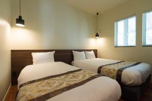 - 2 lits dans une chambre avec 2 fenêtres dans l'établissement Mihana恩納村, à Onna