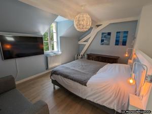 una camera da letto con un letto, una TV e un divano di Séjour de charme à Mareau-aux-Bois : parc, home cinéma, billard, tennis et télétravail en fibre ultra-rapide - FR-1-590-279 a Mareau-aux-Bois