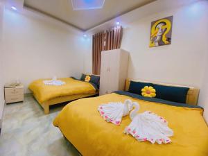 - 2 lits dans une chambre avec des draps jaunes dans l'établissement Vĩnh Hà Motel, à Trai Mat