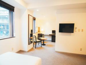 a hotel room with a desk and a television at Quintessa Hotel Kokura Comic & Books in Kitakyushu