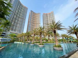 een groot zwembad met palmbomen in een stad bij Gold Coast Sea View Apartments by Rentrooms in Jakarta