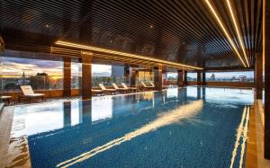 a large swimming pool with chairs in a building at Horison Diana Timika in Timika