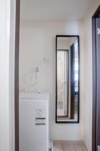 a bathroom with a mirror and a white refrigerator at 桜の宿 in Osaka