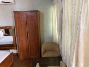 - une chambre avec un lit, une chaise et une armoire dans l'établissement Hotel Bel Azur Hillacondji, à Hila-Kondji