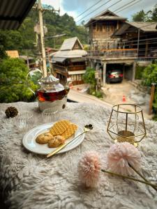 a table with a plate of food and a cup of tea at บ้านพักกึ๊ดเติง แม่กำปอง เชียงใหม่ in Mae On
