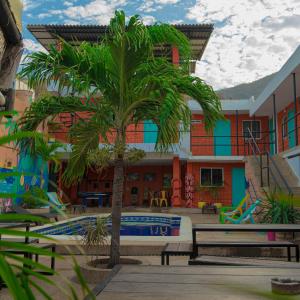 a palm tree in front of a building with a pool at Hostel Nirvana Taganga in Taganga