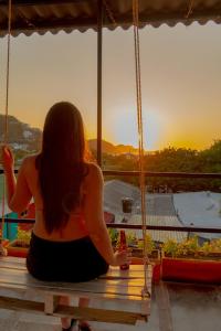a woman sitting on a swing watching the sunset at Hostel Nirvana Taganga in Taganga