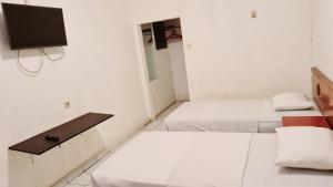 2 camas en una habitación con TV en la pared en Acirasa Homestay Medan, en Medan