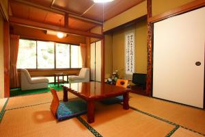 a living room with a wooden table and chairs and a room at Dainichiya-ryokan in Sasaguri
