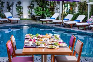 a table with food next to a swimming pool at ÊMM Hotel Hue in Hue