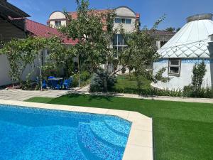 a swimming pool in a yard with a house at Tunduk Hostel in Bishkek