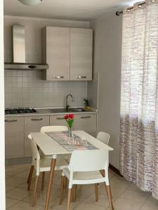 una cocina con una mesa blanca con sillas y un jarrón de flores en Casa Magenta Apartment 1, en Valeggio sul Mincio