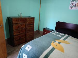 a bedroom with a bed and a wooden dresser at Casa VillaOliva in Ciudad Lujan de Cuyo