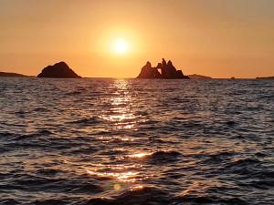 un coucher de soleil sur l'océan avec des rochers dans l'eau dans l'établissement Porquerolles - Nuit insolite à bord du Défi Fou, à Porquerolles