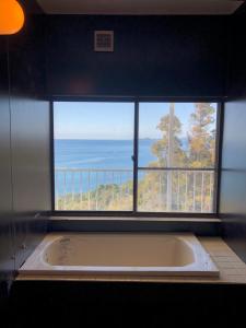 a bath tub in a room with a large window at Cliff top Terrace in Kuranomoto