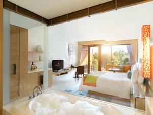 a bedroom with a king bed and a bath tub at Renaissance Phuket Resort & Spa in Mai Khao Beach