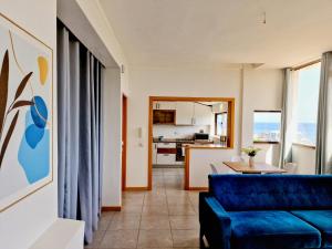 a living room with a blue couch and a kitchen at Kelly Guest House in Praia