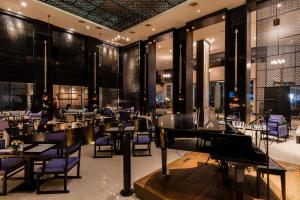 The Royal Paradise Hotel & Spa - SHA Extra Plus في شاطيء باتونغ: مطعم فيه كراسي أرجوانية وطاولات وبيانو