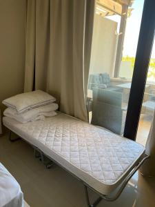 uma cama num quarto ao lado de uma janela em Cozy new townhouse for 6 people! em Salalah