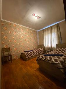 a bedroom with two beds and floral wallpaper at Guesthouse SVANURI SAKHLI in Ushguli