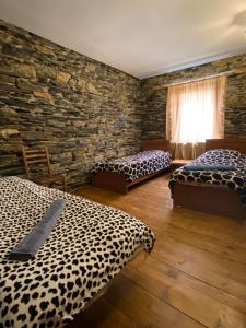 a room with two beds and a stone wall at Guesthouse SVANURI SAKHLI in Ushguli