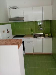 eine Küche mit weißen Schränken und grünen Fliesen in der Unterkunft Martin in Belgrad