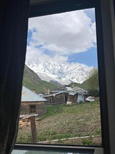 uma vista para uma montanha coberta de neve através de uma janela em Guesthouse SVANURI SAKHLI em Ushguli