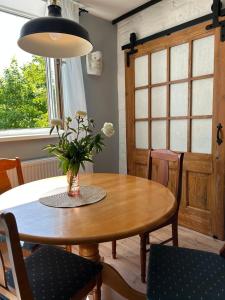 una mesa de comedor con un jarrón de flores. en Mareena_apartments en Liepāja