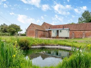 an old brick building with a pond in front of it at Longwool Lookout in Hemingby