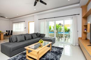 ein Wohnzimmer mit einem grauen Sofa und einem Couchtisch aus Glas in der Unterkunft Relax Pool Villa Near Walking Street,jacuzzi ,BBQ 5Bed 6Bath City house54 in Pattaya South