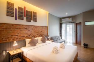 1 dormitorio con 1 cama grande y pared de ladrillo en The Old City Wall Inn en Chiang Mai