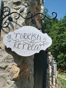 una señal que dice retirada turca colgando de una pared de piedra en Turkish Retreat, en Saadet