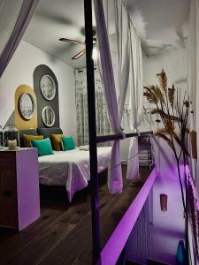 a bedroom with a bed with purple and green pillows at La Casita del Abuelo Valentín 