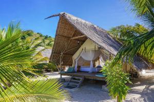 a small tent on the beach with palm trees at Le Pirate Island - Adults Only in Labuan Bajo