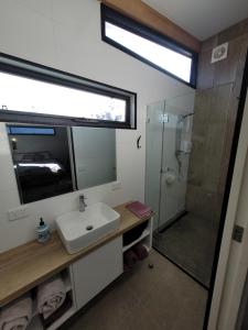 a bathroom with a sink and a shower with a mirror at Bayside Bungalow in Cheltenham