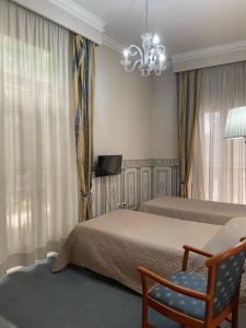 1 dormitorio con 2 camas, silla y lámpara de araña en City Hall, en Catania