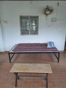 a bed in a room with a bench and a window at Whispering Winds in Pune