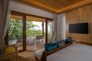 Schlafzimmer mit einem Bett, einem TV und einem Balkon in der Unterkunft Sinae Phuket - SHA Extra Plus in Phuket