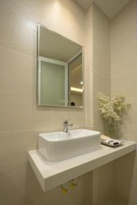 ein Badezimmer mit einem weißen Waschbecken und einem Spiegel in der Unterkunft Karat Home in Ho-Chi-Minh-Stadt
