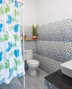 a bathroom with a toilet and a shower curtain at Sanssouci Kep in Kep