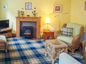 a living room with a fireplace and chairs and a tv at The Bothy At Willowbank in Grantown on Spey
