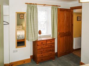 a bedroom with a bed and a dresser and a window at The Bothy At Willowbank in Grantown on Spey