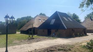 Eine Scheune mit schwarzem Dach, vor der eine Person sitzt. in der Unterkunft Tiny House Aqualinde in Breda